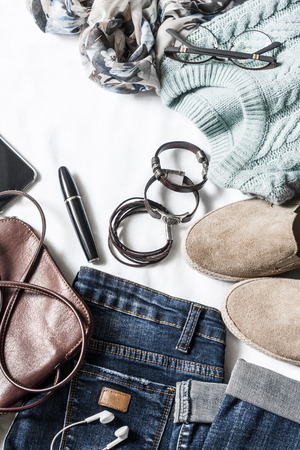 Women's autumn clothing set - jeans, suede sneakers, pullover, scarf and leather bag. Women's clothes for autumn walks on a light background, top view. Flat lay, copy spaceの写真素材