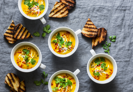 Turmeric pumpkin vegetarian soup on grey background, top view. Flat lay butternut squash soup served...