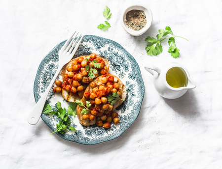 Spicy chickpeas in tomato sauce toast - delicious snack on a light background, top viewの写真素材