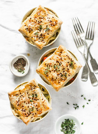 Chicken and seasonal vegetables portion pot pie on a light background, top view. Flat layの写真素材