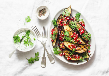 Baked eggplant with feta, greek yogurt, cilantro sauce and pomegranate seeds on light background, top view. Delicious snack, tapas, appetizersの写真素材