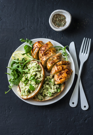 Roasted chicken breast and avocado toast - healthy lunch on a dark background, top viewの写真素材