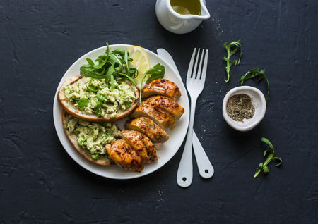 Roasted chicken breast and avocado toast - healthy lunch on a dark background, top viewの写真素材