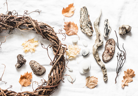 Natural nature objects for creative crafts - vine wreath, stones, leaves, wood on a light background, top view. Homemade creativity conceptの写真素材