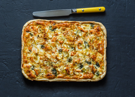 Salmon, leek, spinach, cheese puff pastry pie on dark background, top viewの写真素材