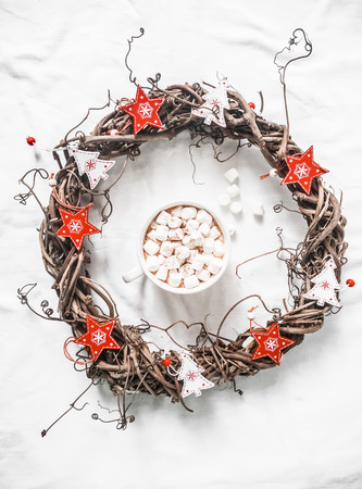 Homemade Christmas vine wreath with red wooden stars and hot chocolate with marshmallows on white background, top view. Copy space, flat layの写真素材