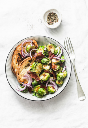 Roasted brussels sprouts with bacon on a light background, top view. Delicious appetizers or snacksの写真素材
