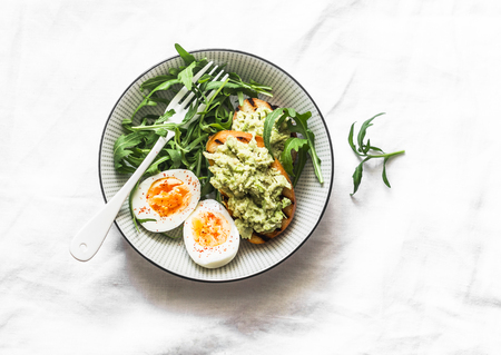 Healthy breakfast or snack - mashed avocado sandwich and boiled egg on a light background, top viewの写真素材
