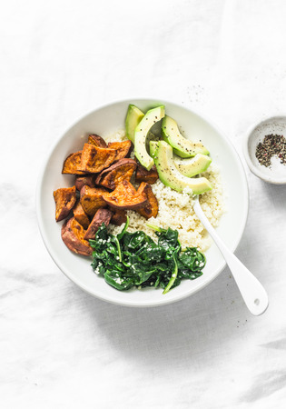 Sweet potato, couscous, spinach, avocado buddha bowl on light background, top view. Vegetarian comfort food conceptの写真素材