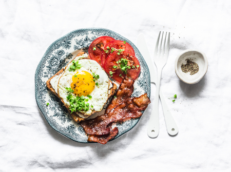 Nutritious breakfast - fried egg toast, bacon and tomatoes on a light background, top viewの写真素材