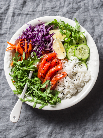 Smoked salmon, rice, vegetables buddha power bowl on gray background, top view. Red cabbage, carrots, arugula, rice, smoked salmon fish bowl. Healthy food conceptの写真素材