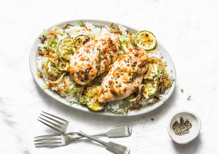 Dijon baked chicken with rice, courgettes and fried onions on light background, top viewの写真素材