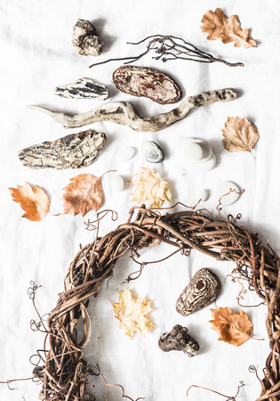 Natural nature objects for creative crafts - vine wreath, stones, leaves, wood on a light background, top view. Homemade creativity conceptの写真素材