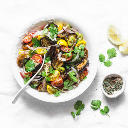 Marinated eggplant, sweet tomato and cilantro mediterranean style salad on light background, top view. Vegetarian food conceptの写真素材