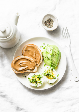Peanut butter toasts, boiled egg with micro greens, avocado - healthy breakfast or snack on a light background, top viewの写真素材