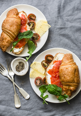 Brunch or breakfast table - croissants with cream cheese and smoked salmon,  and cherry tomatoes. Delicious balanced breakfast, brunch or snack on a grey background, top viewの写真素材