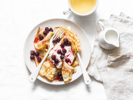 Crepes with cherry sauce and cream on a light background, top view. Delicious breakfast, dessertの写真素材