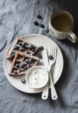 Gluten free chocolate waffles with cream and blueberries and coffee on a grey background, top view. Breakfast tableの写真素材