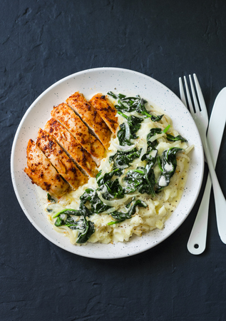 Baked chicken breast, mashed potatoes with creamy spinach on dark background, top view. Comfort foodの写真素材