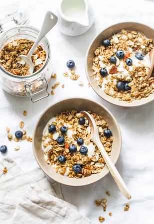 Homemade peanut butter granola with greek yogurt and blueberries on a light background, top view. Healthy energy breakfast or snack. Flat layの写真素材