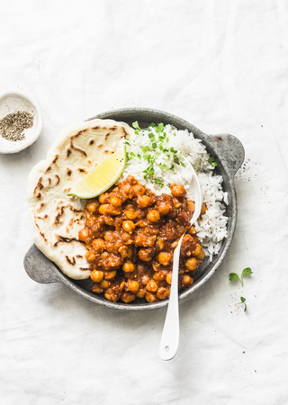 Indian spicy chickpeas curry with rice and naan bread in pan on light background, top view. Healthy delicious vegetarian foodの写真素材