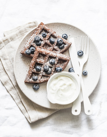 Gluten free chocolate waffles with cream and blueberries on a light background, top viewの写真素材