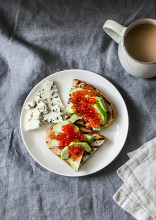 Delicious breakfast or snack - red caviar, avocado sandwiches and blue cheese on grey background, top viewの写真素材