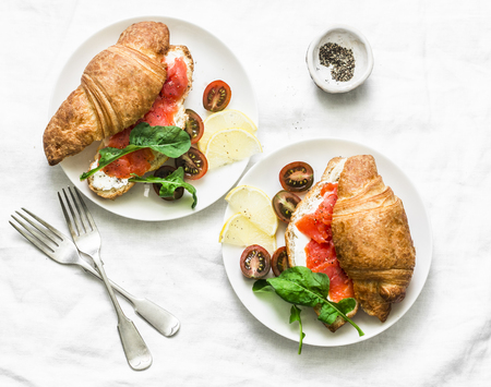 Brunch or breakfast table - croissants with cream cheese and smoked salmon,  and cherry tomatoes. Delicious balanced breakfast, brunch or snack on a light background, top viewの写真素材