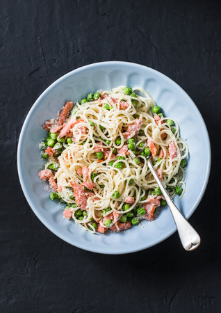 Smoked salmon, green peas, creamy sauce spaghetti  - delicious lunch in the mediterranean style. On a dark background, top viewの写真素材