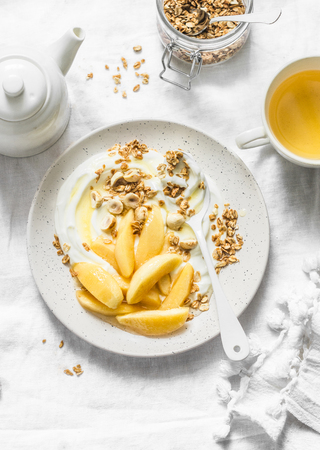 Caramelized quince with Greek yogurt, granola and nuts on a light background, top view. Delicious healthy breakfast, brunch, snackの写真素材