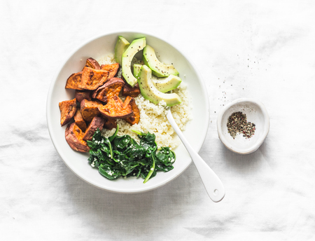 Sweet potato, couscous, spinach, avocado buddha bowl on light background, top view. Vegetarian comfort food conceptの写真素材