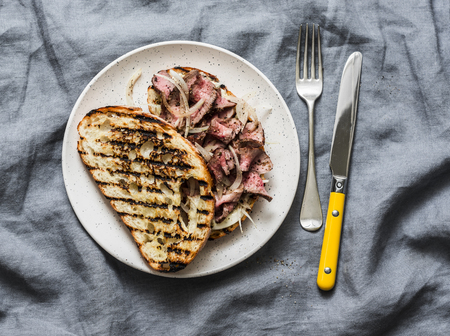 Medium rare beef steak ciabatta sandwiches with marinated onions and homemade mayonnaise mustard sauce on grey background, top viewの写真素材