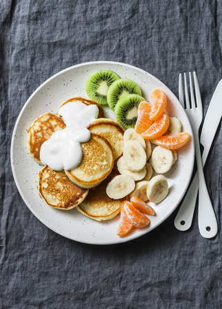 Delicious breakfast or snack - pancakes with fruit and sour cream on a grey background, top view. Baby foodの写真素材