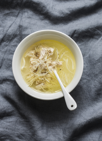 Easy chicken broth with chicken meat, onion and pepper. Soup base on a gray background, top viewの写真素材