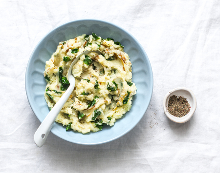 Mashed potatoes with spinach and crispy fried onions on a light background, top view. Delicious side dish or vegetarian mealの写真素材