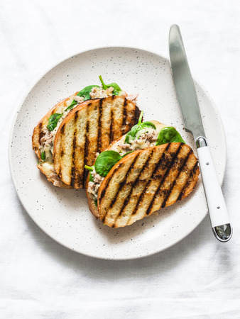 Canned tuna, mozzarella cheese, spinach hot sandwiches on a light background, top view. Delicious breakfast, brunch, tapas, snackの写真素材