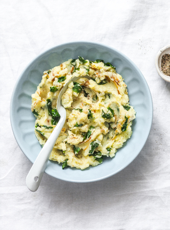 Mashed potatoes with spinach and crispy fried onions on a light background, top view. Delicious side dish or vegetarian mealの写真素材