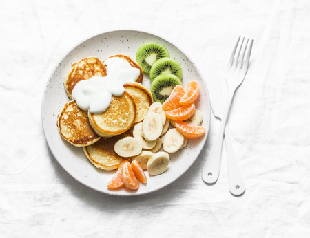 Delicious breakfast or snack - pancakes with fruit and sour cream on a light background, top view. Baby foodの写真素材