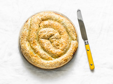 Spinach, garden spring herbs, fresh ricotta puff pastry pie on a light background, top viewの写真素材