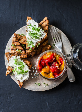 Marinated baked sweet pepper, whole grain toast with cream cheese - tasty snack, appetizers, tapas on a dark background, top viewの写真素材