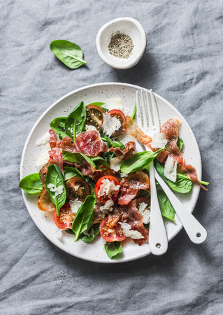 Crispy prosciutto, cherry tomatoes, spinach, parmesan salad on grey background, top view. Delicious appetizersの写真素材