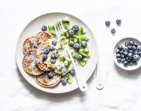 Gluten free pancakes with coconut yogurt, kiwi and blueberries on a light background, top viewの写真素材