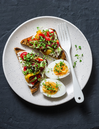 Healthy breakfast or snack - whole grain bread, feta, pickled pepper sandwiches and boiled egg on dark background, top viewの写真素材