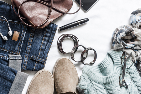 Women's spring clothing set - jeans, suede sneakers, pullover, scarf and leather bag. Women's clothes for spring walks on a light background, top view. Flat lay, copy spaceの写真素材