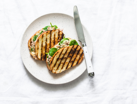 Canned tuna, mozzarella cheese, spinach hot sandwiches on a light background, top view. Delicious breakfast, brunch, tapas, snackの写真素材