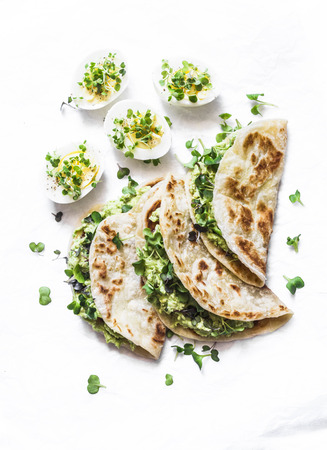 Avocado cream cheese micro greens quesadilla and boiled eggs on a light background, top view. Delicious healthy breakfast, snack, brunch. Flat layの写真素材