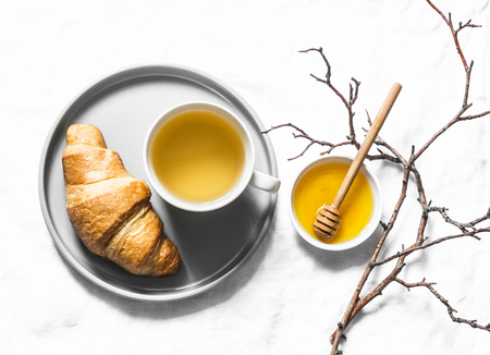 Tea time. Green tea with honey and croissant on a light background, top viewの写真素材