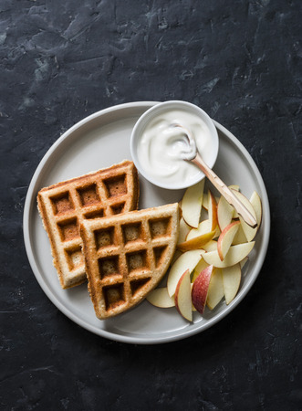 Banana oatmeal waffles with apple and yogurt on a dark background, top view. Delicious breakfast, dessertの写真素材