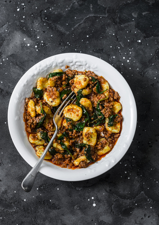 Pumpkin gnocchi with bolognese sauce and spinach on a dark background, top viewの写真素材