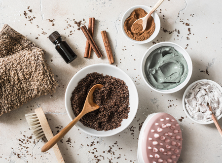 Home anti-cellulite products - coffee scrub, cosmetic clay, essential orange oil, hand anti-cellulite massage, nut scrub, cinnamon, natural loofah on a light background, top view. Beautiful healthy body conceptの写真素材